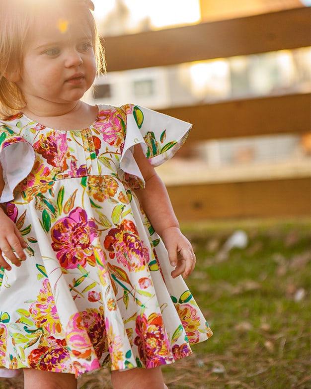 Simple Life Pattern Co. | Baby Ivy's Angel Sleeve Top & Dress. Downloadable PDF Sewing Pattern for Babies Size Newborn to 24 Months. Ivy is a sweet vintage inspired beauty! Ivy's Angel Sleeve Top & Dress features babydoll style bodice that can be sewn simple or with the optional pin tuck placket for such a sweet look.  The angel sleeves on Ivy give this pattern such a feminine and sweet look.  It can also be made sleeveless if you prefer.  There are 3 skirt options for Ivy: a top length, vintage length, and a knee-length! The skirt has options for a simple gathered skirt or circle skirt that is sure to have your girl twirling the day away! The look is finished with a beautiful circle keyhole in the back with a tie closure.  